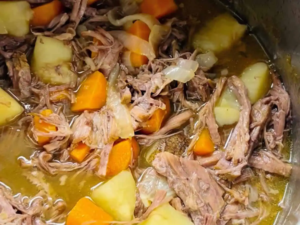 An Instant Pot filled pot roast, showing tender beef and chunks of potatoes and carrots.