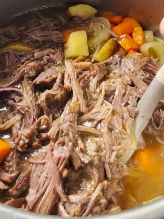 An Instant Pot filled pot roast, showing tender beef and chunks of potatoes and carrots.