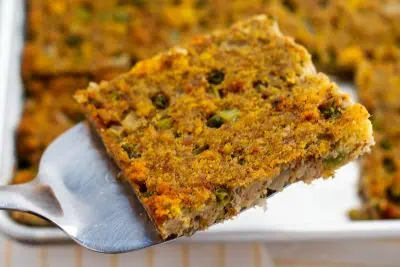 Closeup of a slice of Southern cornbread dressing on a spatula.