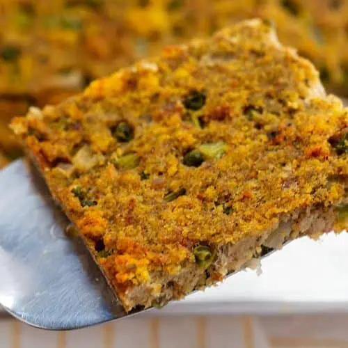 Closeup of a slice of Southern cornbread dressing on a spatula.