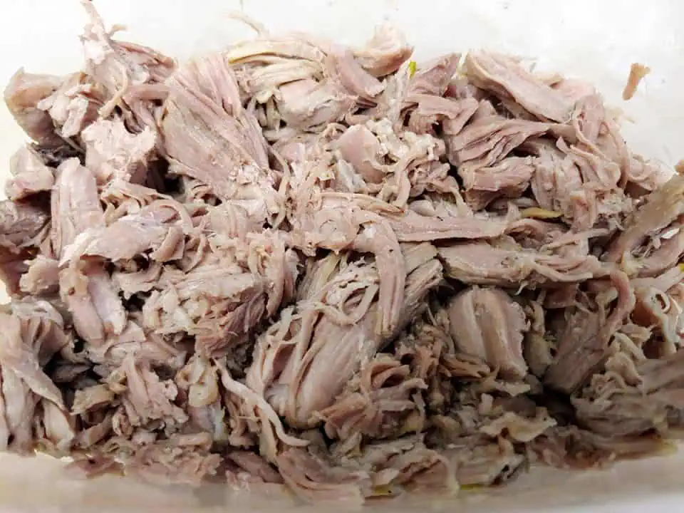 Shredded turkey on white cutting board.