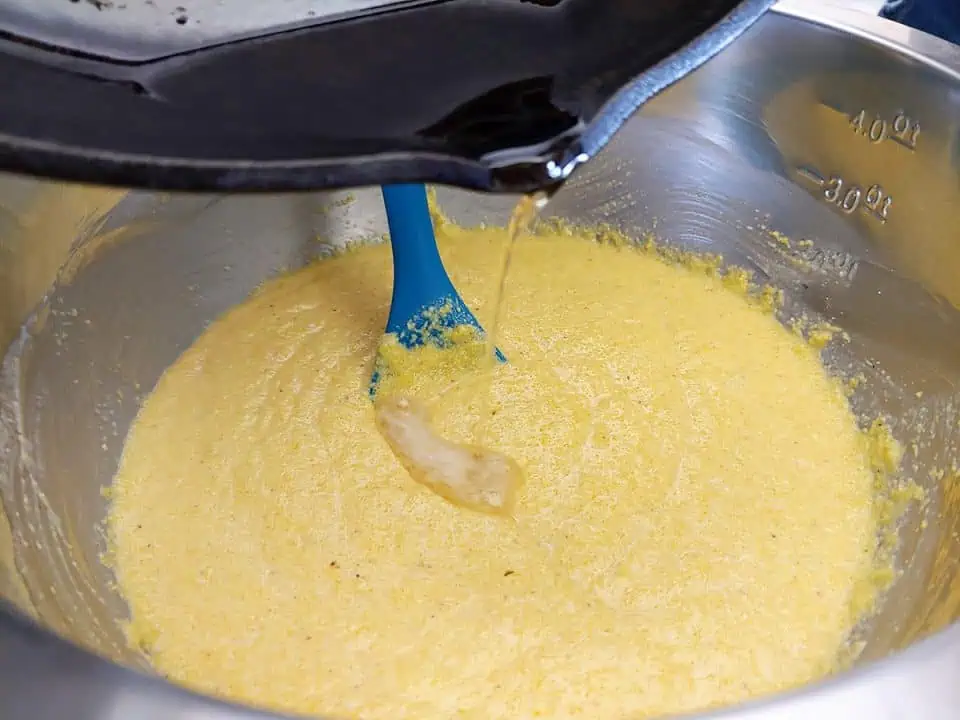 Pouring hot bacon fat into cornbread batter.