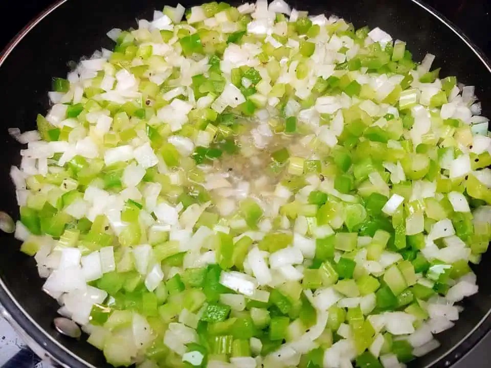 Sautéing onions, peppers, and celery in bacon fat.