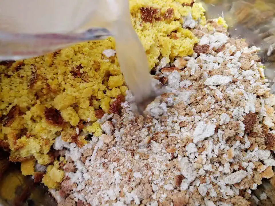 Pouring turkey stock into bowl with crumbled cornbread and stuffing mix.