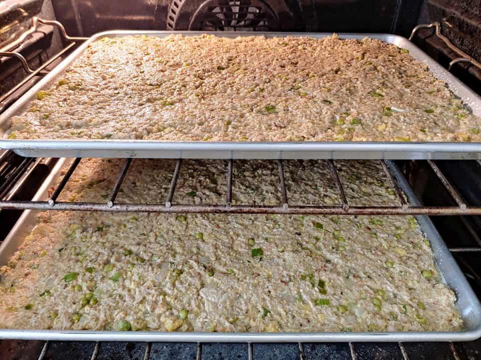 Two pans of Southern cornbread dressing baking in oven.