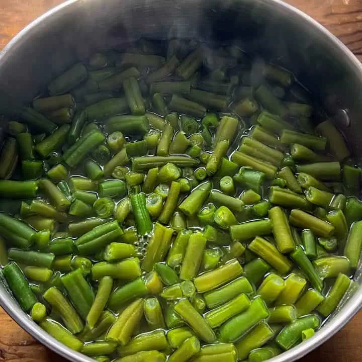 A pot filled with fresh green beans boiling in water.