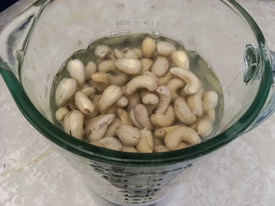 Blender filled with raw cashews and warm water.