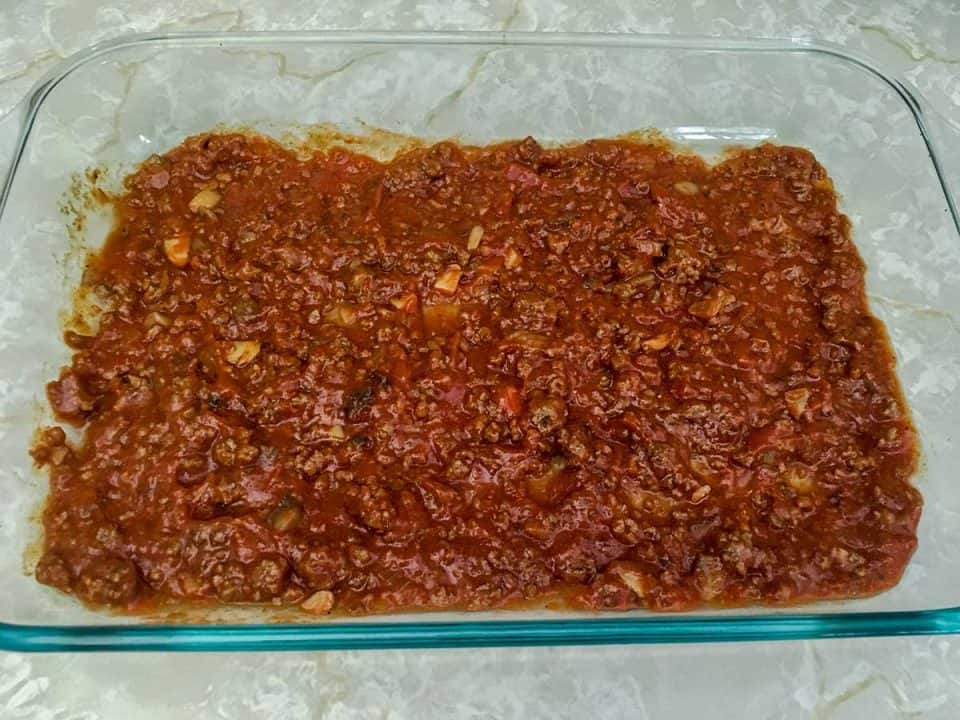 A casserole dish with a layer of meat sauce.
