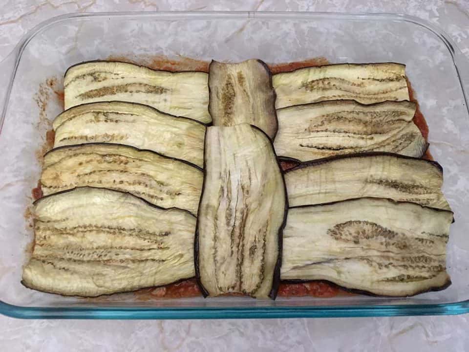 A casserole with a layer of eggplant slices over meat sauce.