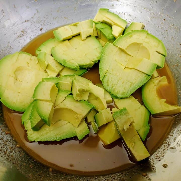 Avocados in large bowl with lime dressing.