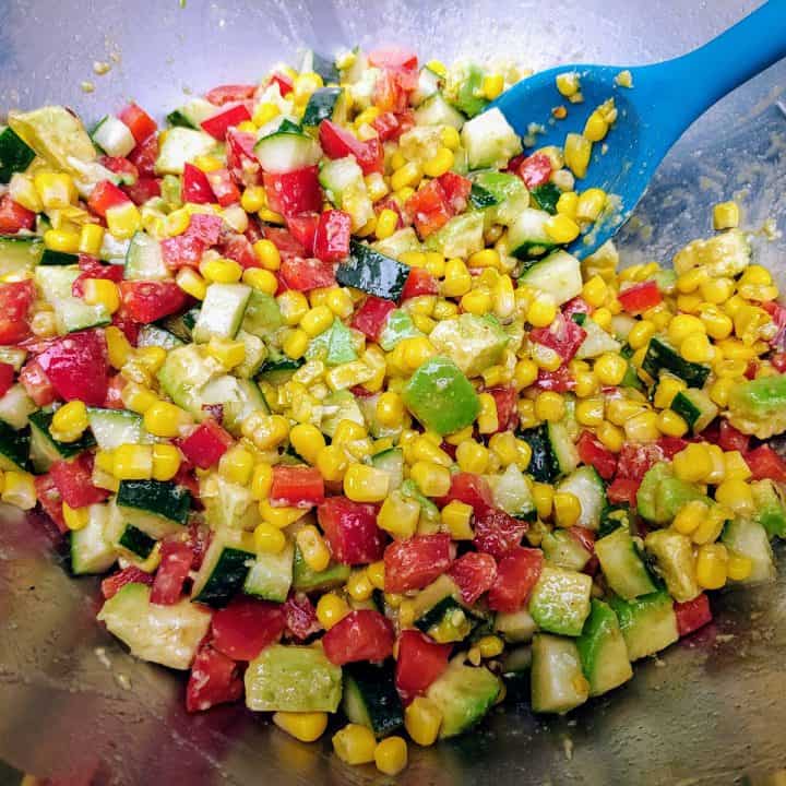 Mixing canned bean salad in large bowl with teal spoon.