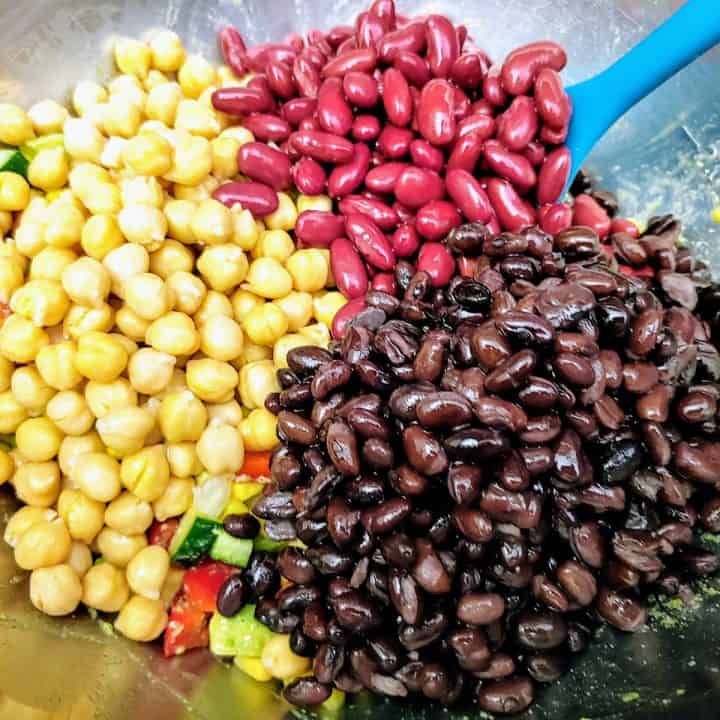 Canned back beans, kidney beans, and chickpeas in large bowl with teal spoon.