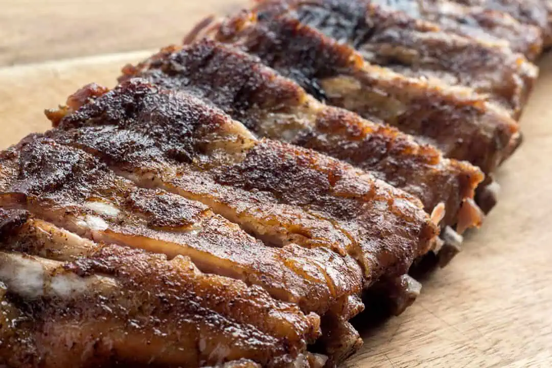 Instant Pot baby back ribs with a dry rub on a wooden cutting board.