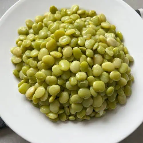 White bowl full of baby lima beans on top of a black and white striped napkin.