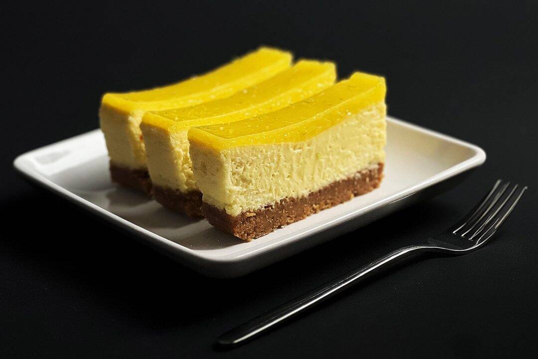 Side view of key lime bars with visible layers of crust, cheesecake, and lime topping, served on a modern square plate
