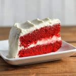 Gluten-free red velvet cake slice with cream cheese frosting on a white plate