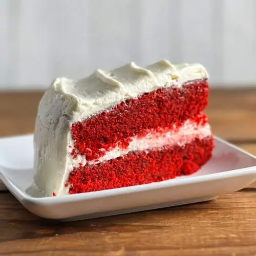 Square closeup of gluten-free red velvet cake with two vibrant layers and cream cheese frosting