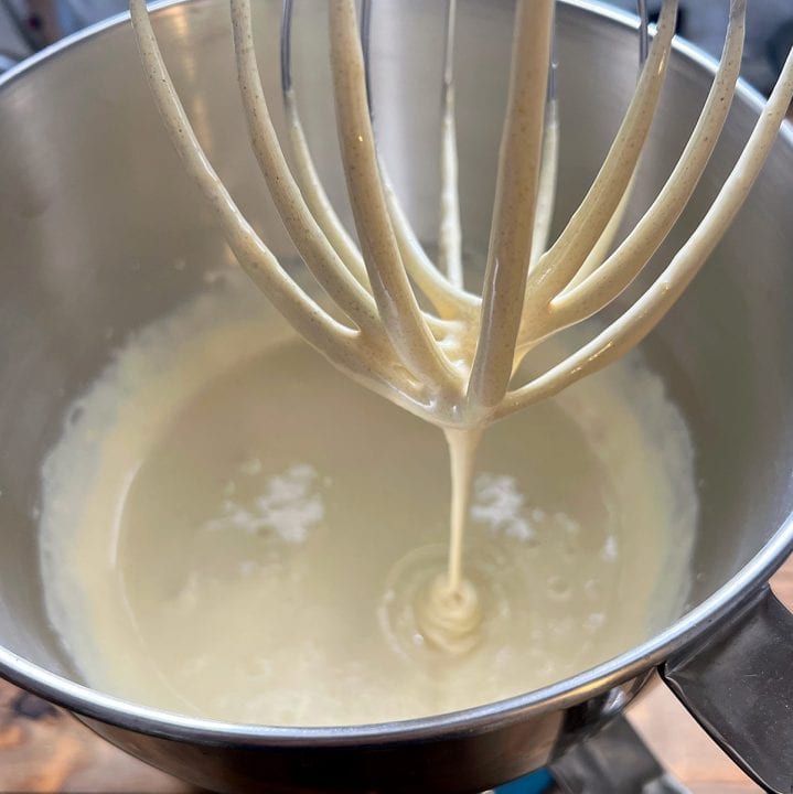 Whipped eggs and sugar in a stand mixer bowl with whisk attachment