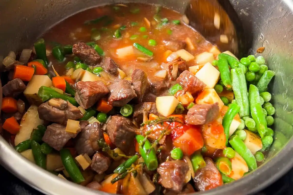 Adding potatoes, carrots, green beans, and peas to soup