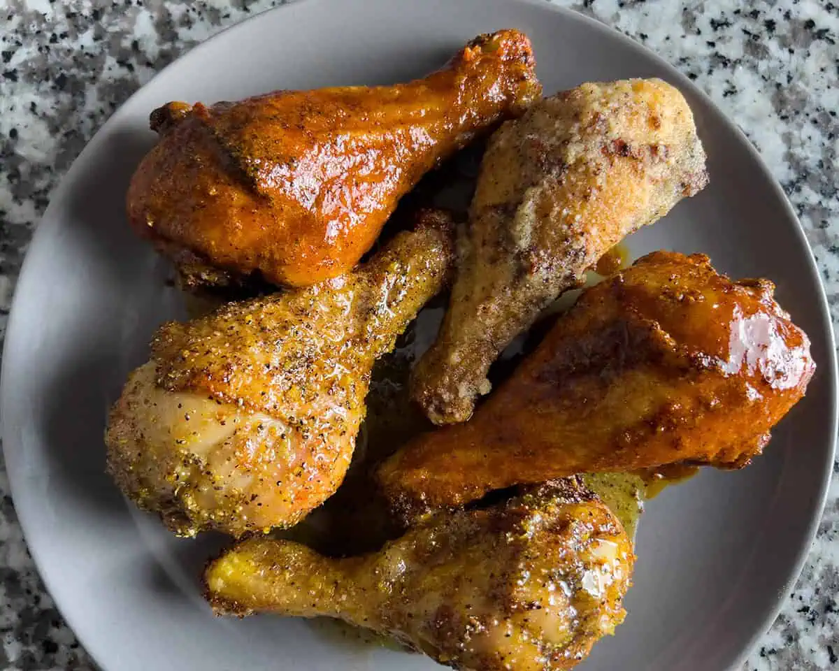 Five drumsticks coated in different finishes with visible spice and sauce sheen.