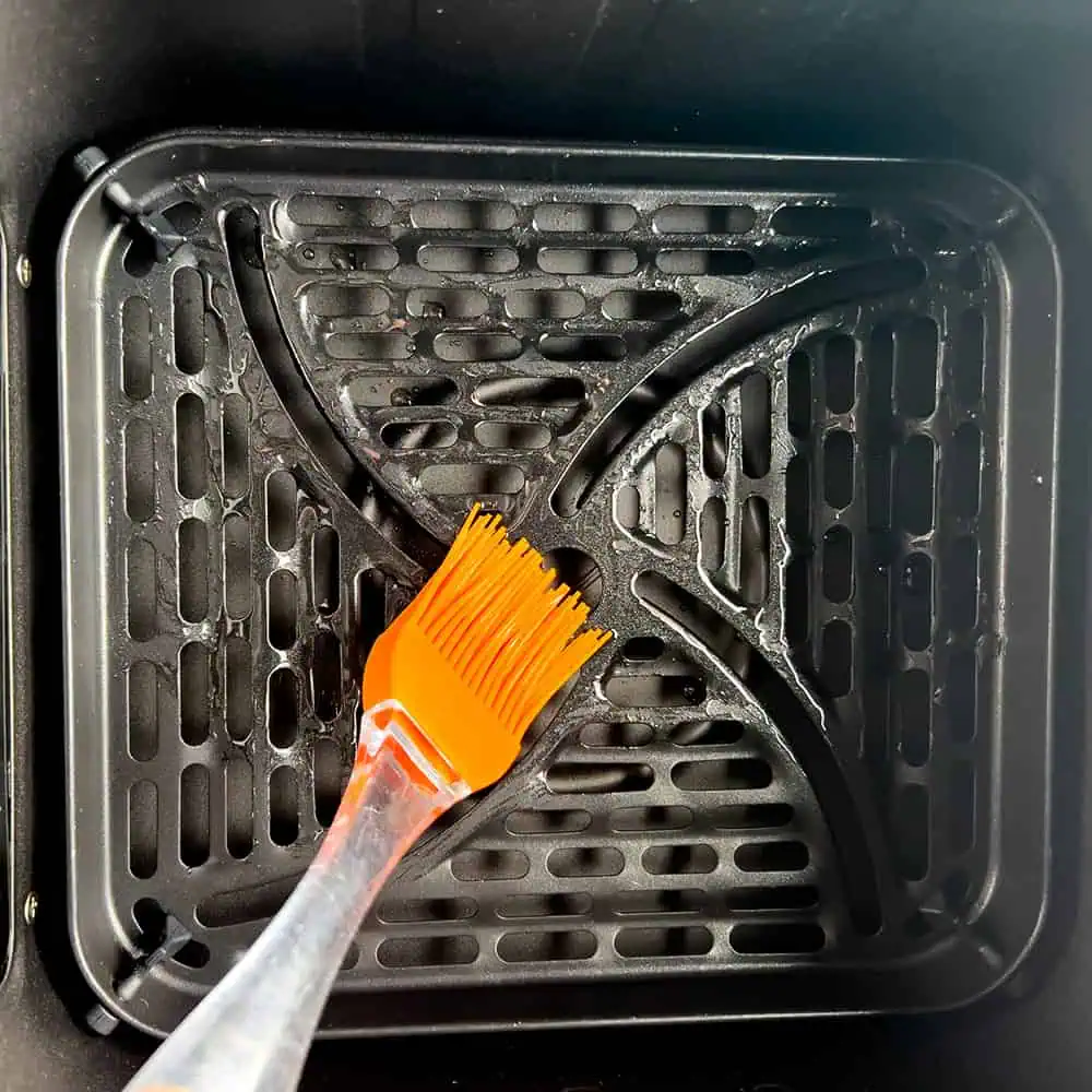 Brushing a thin layer of oil on the air fryer basket to prevent sticking.