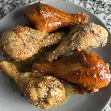 Air fryer chicken drumsticks finished three ways--Nashville hot, lemon-pepper honey, and garlic-Parmesan--on a gray plate.