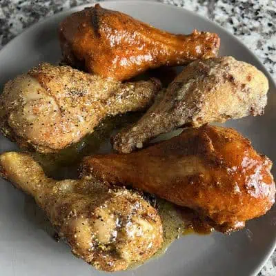 Air fryer chicken drumsticks finished three ways--Nashville hot, lemon-pepper honey, and garlic-Parmesan--on a gray plate.