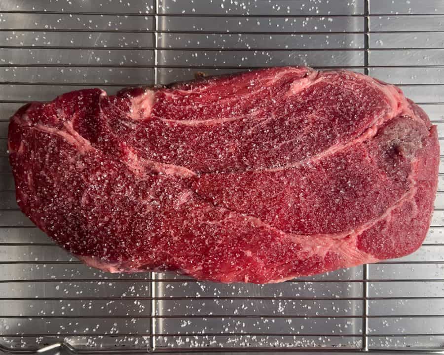 Uncooked chuck roast on a rack, heavily salted for dry brining.
