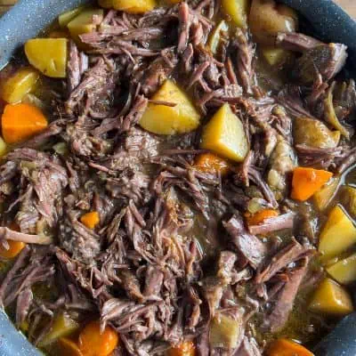 Oven pot roast from top view showing shredded beef and tender vegetables