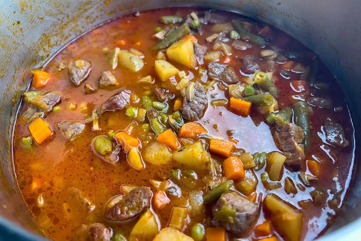 Close-up of hearty vegetable beef soup in the pot with potatoes, carrots, green beans, and tender beef in a rich broth