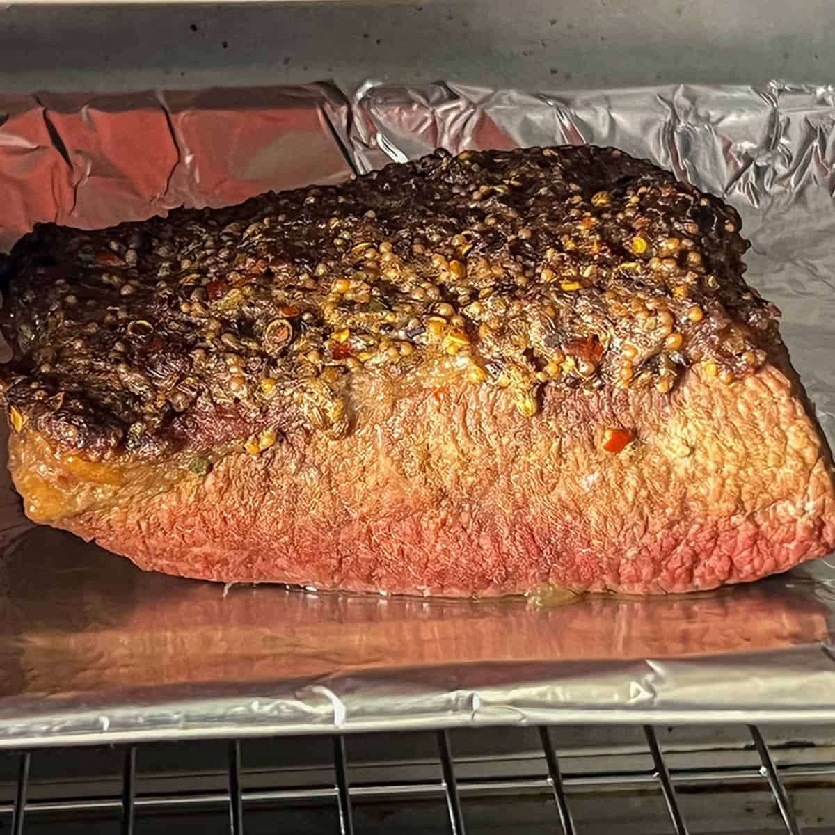 Corned beef under the broiler; fat cap crisping on the bottom rack