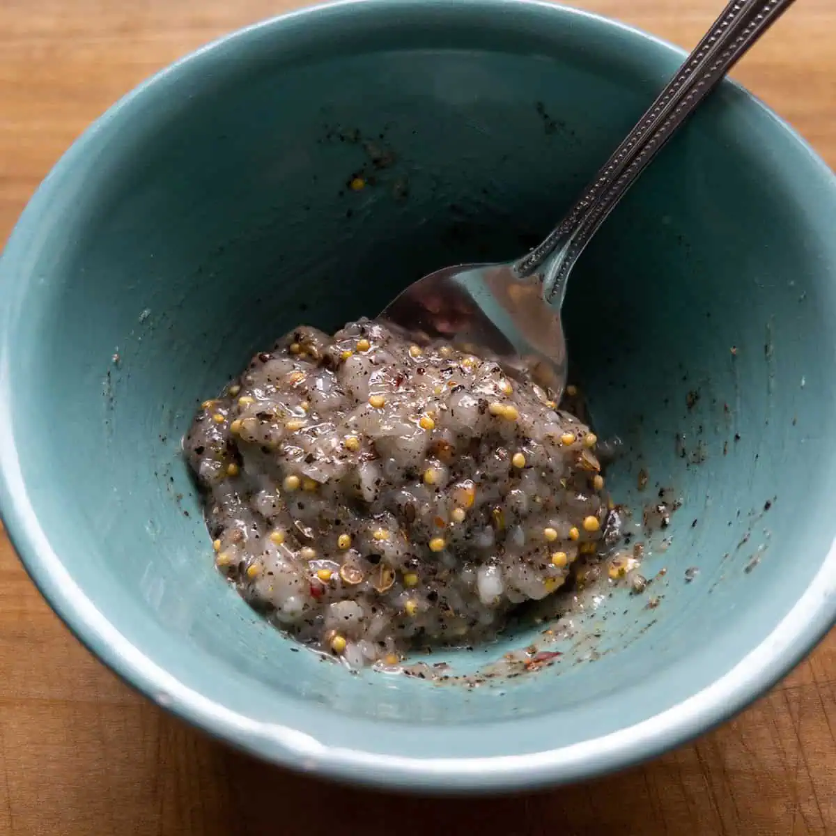 Garlic paste mixed with corned beef seasoning and pepper in a bowl.