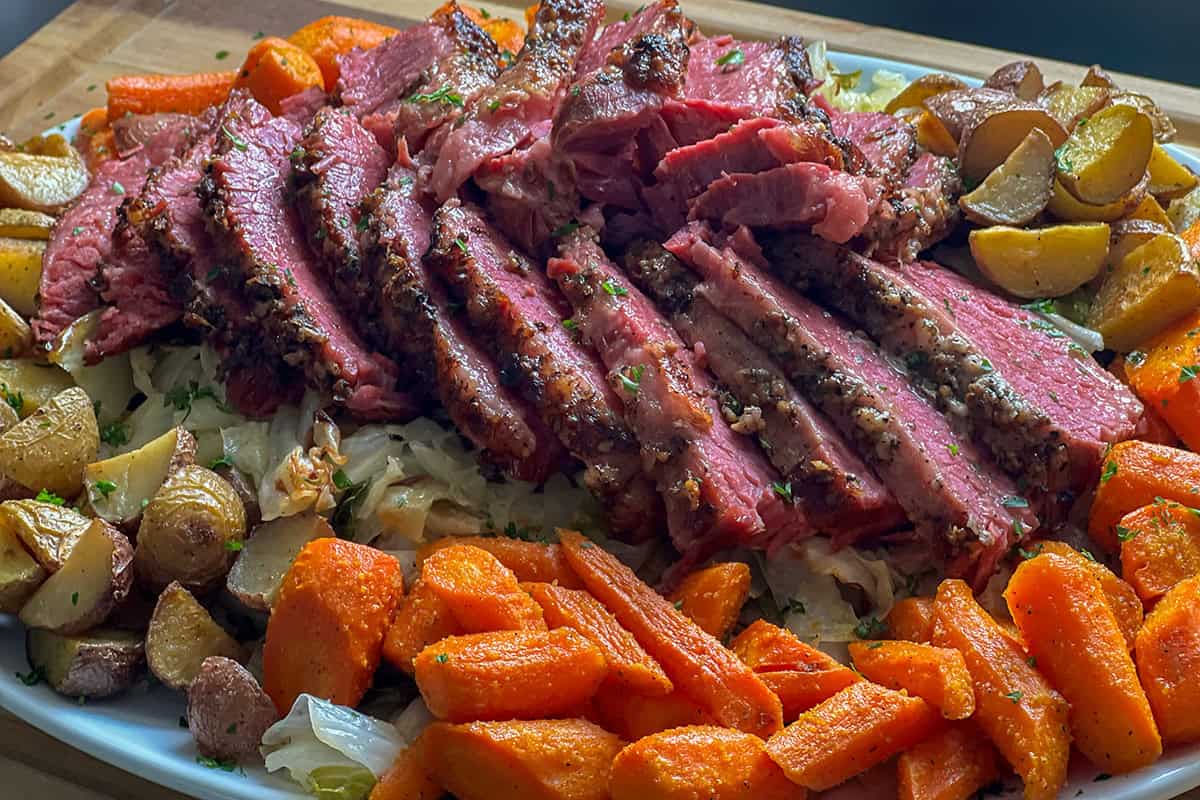 Sliced pressure cooker corned beef with crispy garlic top and vegetables.