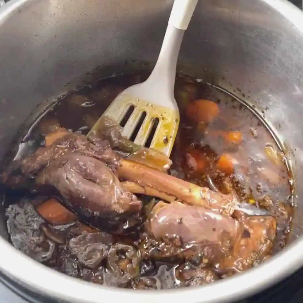 Cooked pressure cooker lamb shanks in braising liquid after natural pressure release in the Instant Pot.