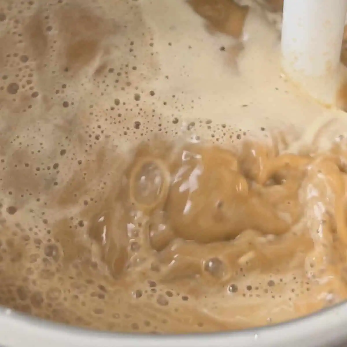 Lamb shank sauce being blended in the pot with an immersion blender until smooth and creamy.