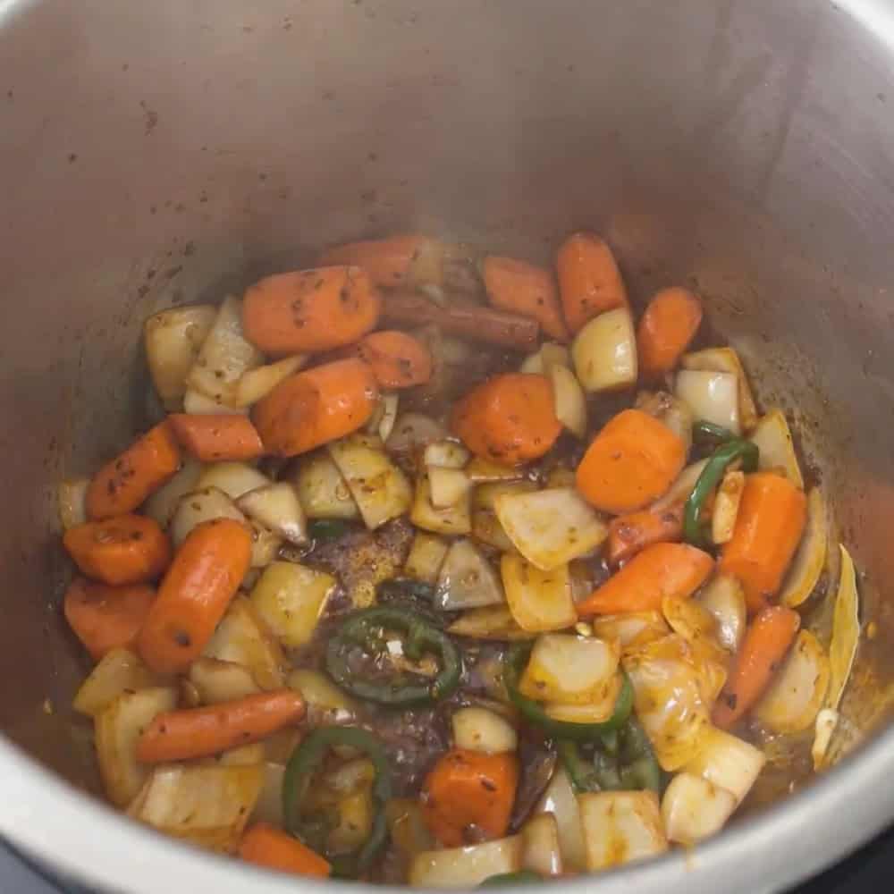 Onions, carrots, and sliced green chile sauteing in the Instant Pot after browning the lamb.