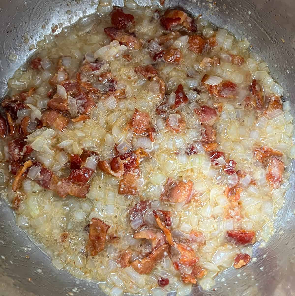 Bacon, onions, and garlic cooking together in the pot.