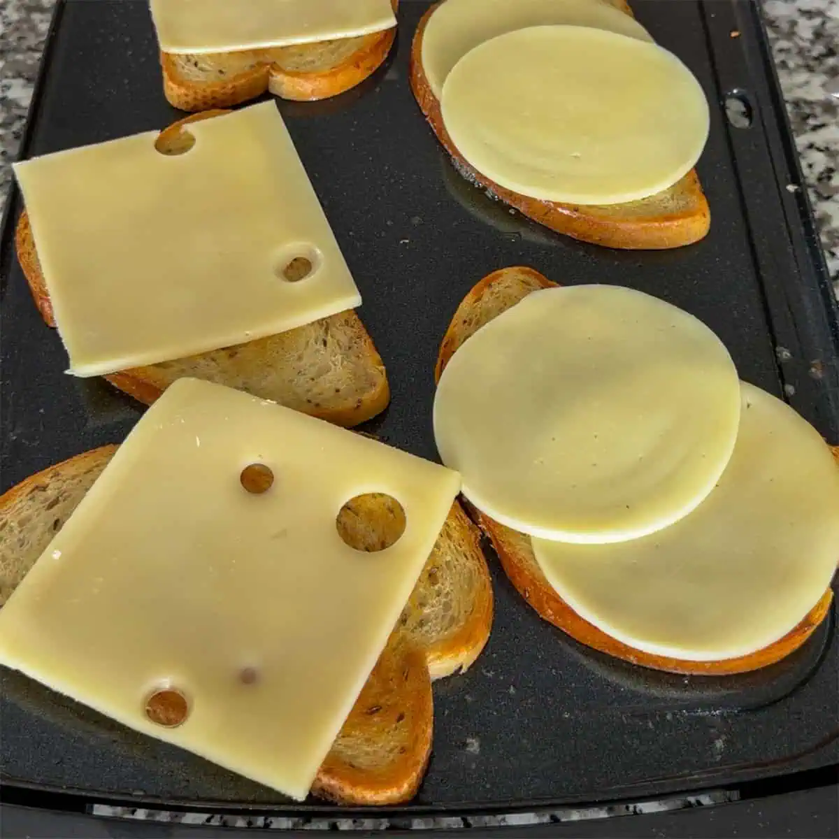 Swiss and provolone melting on toasted rye bread for Gary Reuben sandwiches