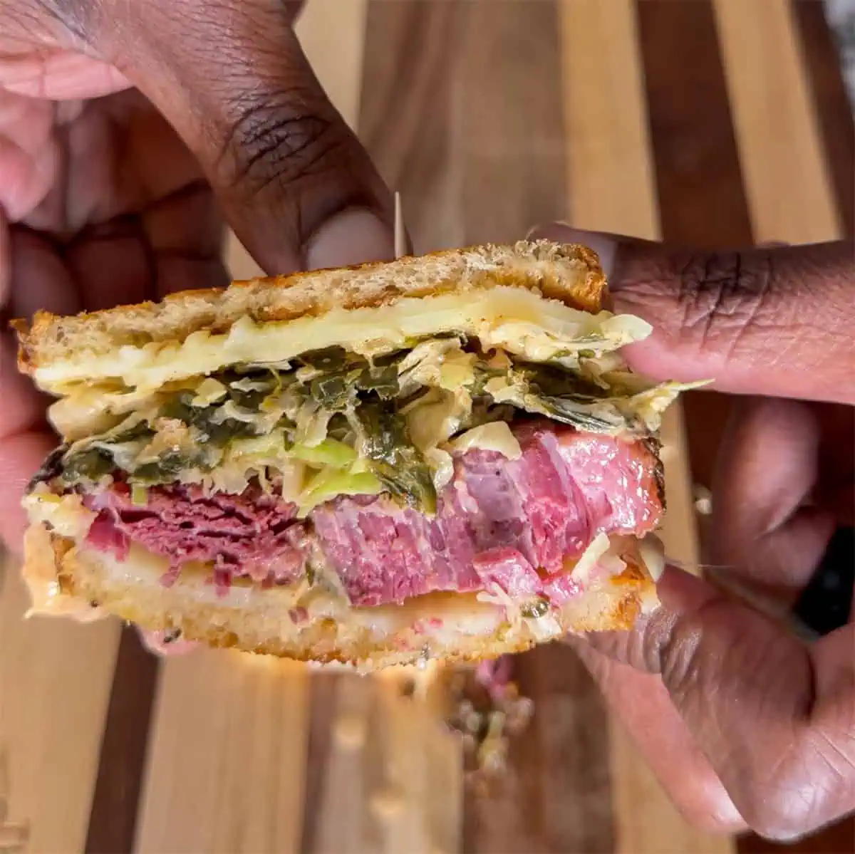 Half of a Gary Reuben sandwich showing corned beef, slaw, and melted cheese