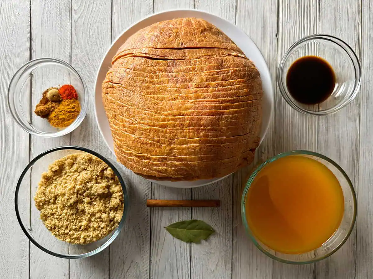 Ingredients for Instant Pot ham including spiral ham, brown sugar, apple cider, Worcestershire sauce, cinnamon stick, bay leaf, and warm spices for the crust.