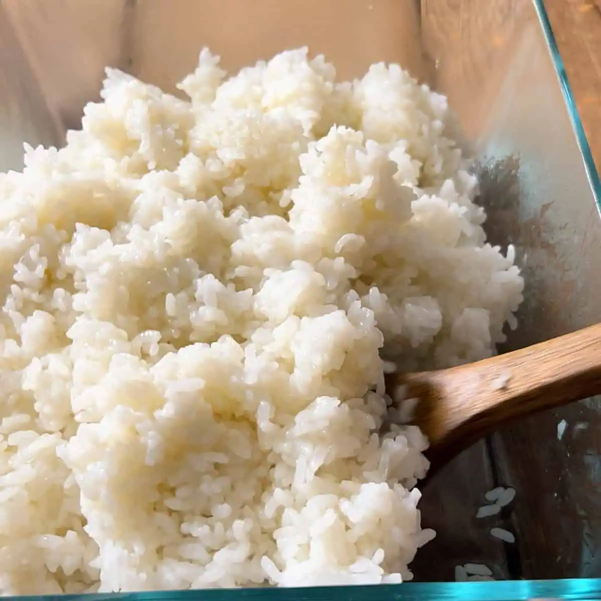 Seasoned Instant Pot sushi rice in a glass dish with a wooden spoon