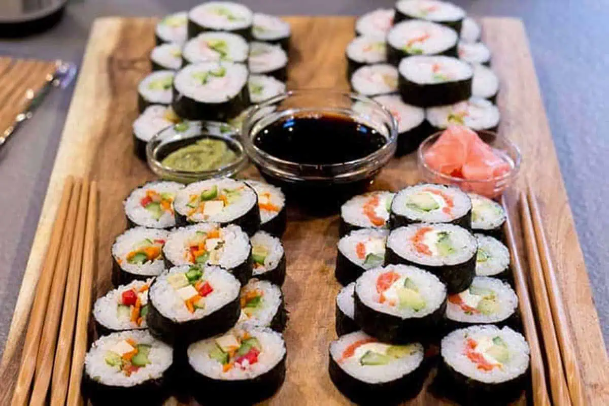 Homemade sushi rolls arranged on a platter with soy sauce, wasabi, and pickled ginger