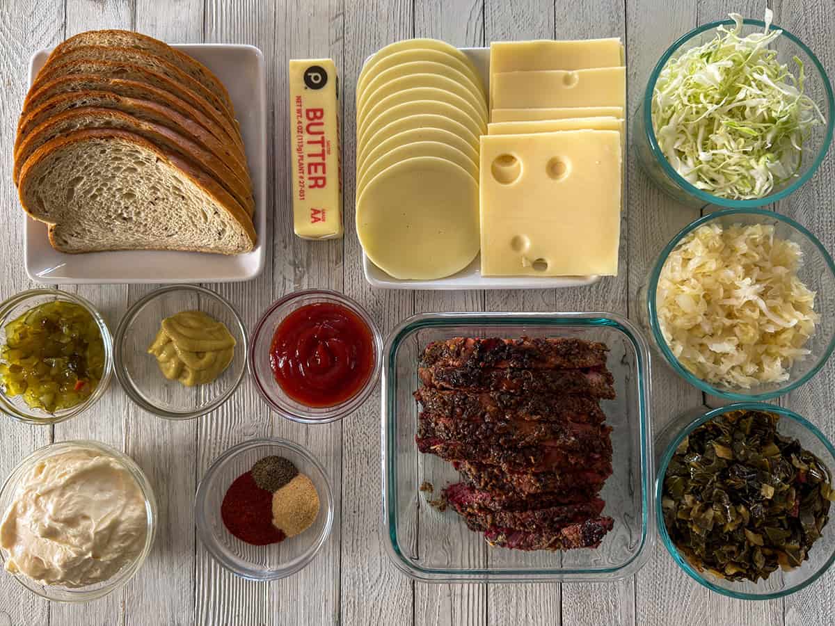 Ingredients for Gary Reuben sandwiches including rye bread, Swiss cheese, provolone, leftover corned beef, cabbage, sauerkraut, collards, mayonnaise, ketchup, mustard, relish, butter, and spices