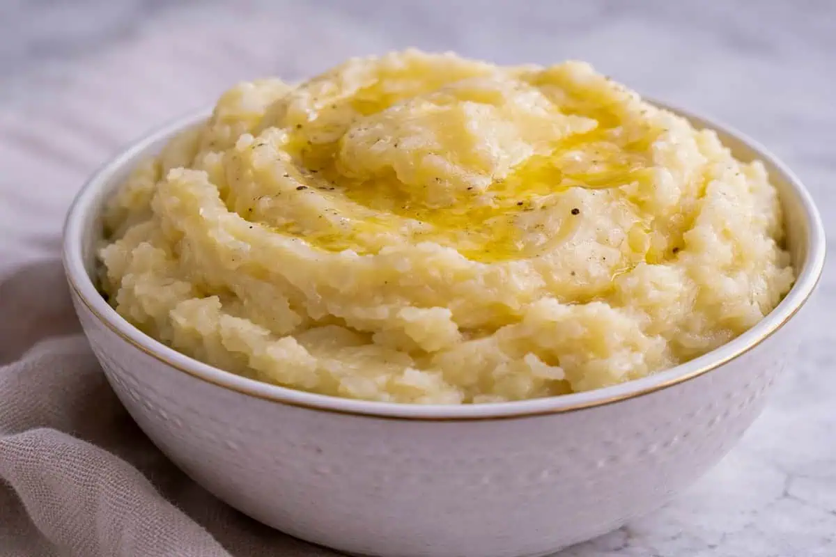 Close-up of mashed potatoes with melted butter on top in a white bowl