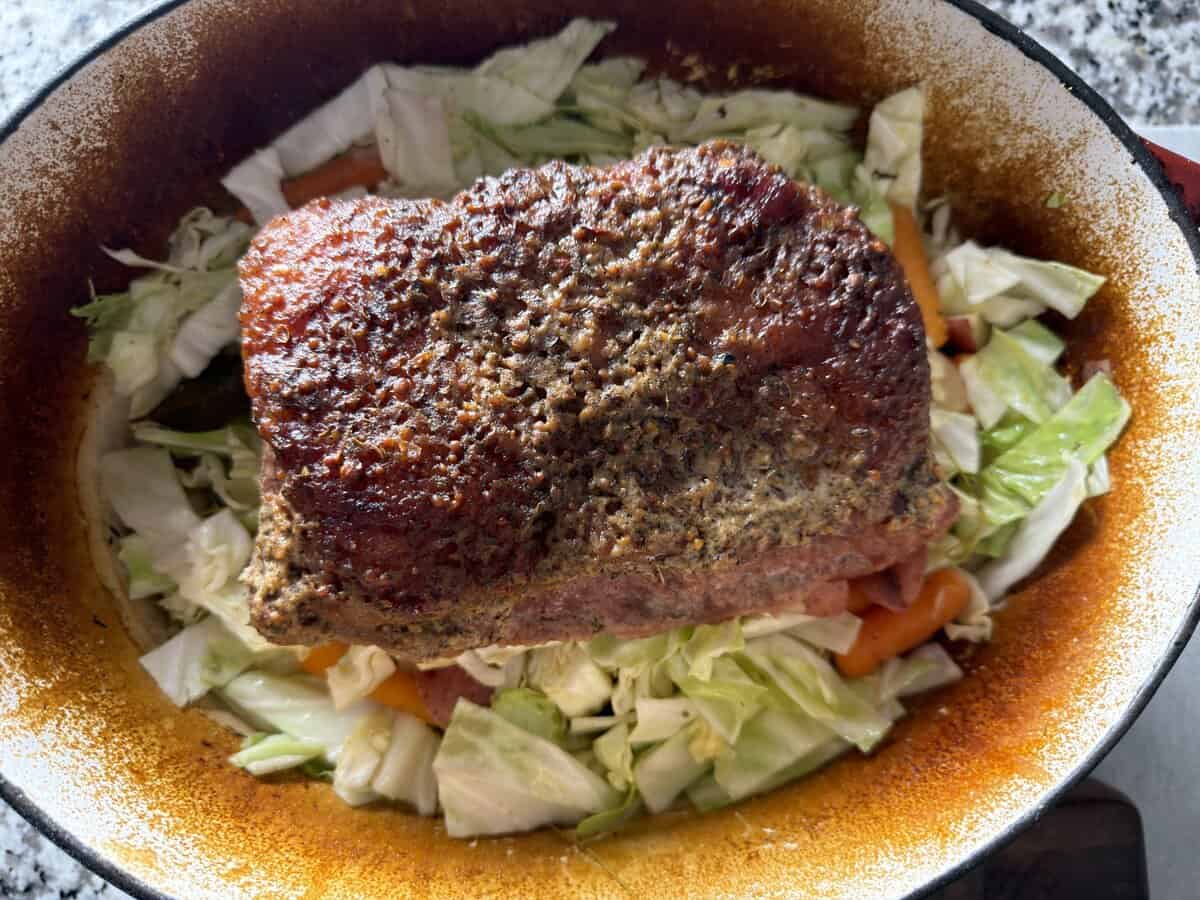 Oven corned beef returned to the Dutch oven on top of cabbage, carrots, and potatoes