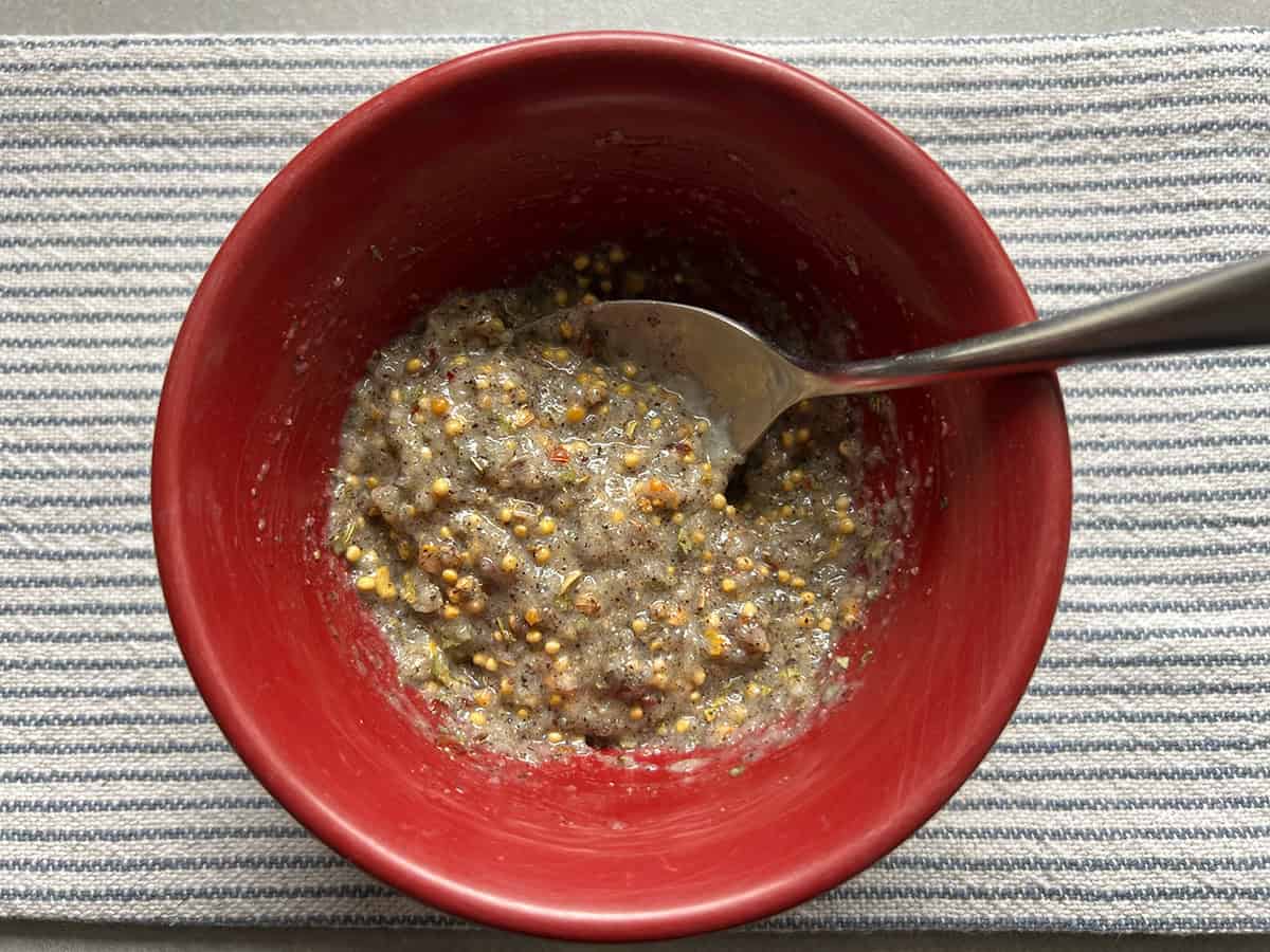 Garlic paste mixed with the corned beef seasoning packet and black pepper in a red bowl.