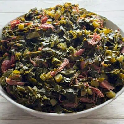 Bowl of southern collard greens cooked with smoked turkey, chopped onions, and pot liquor