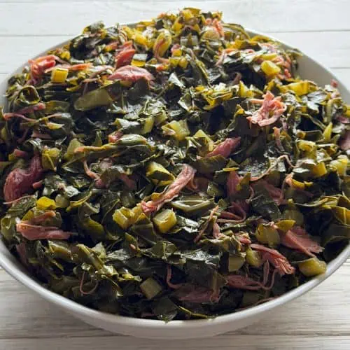 Bowl of southern collard greens cooked with smoked turkey, chopped onions, and pot liquor
