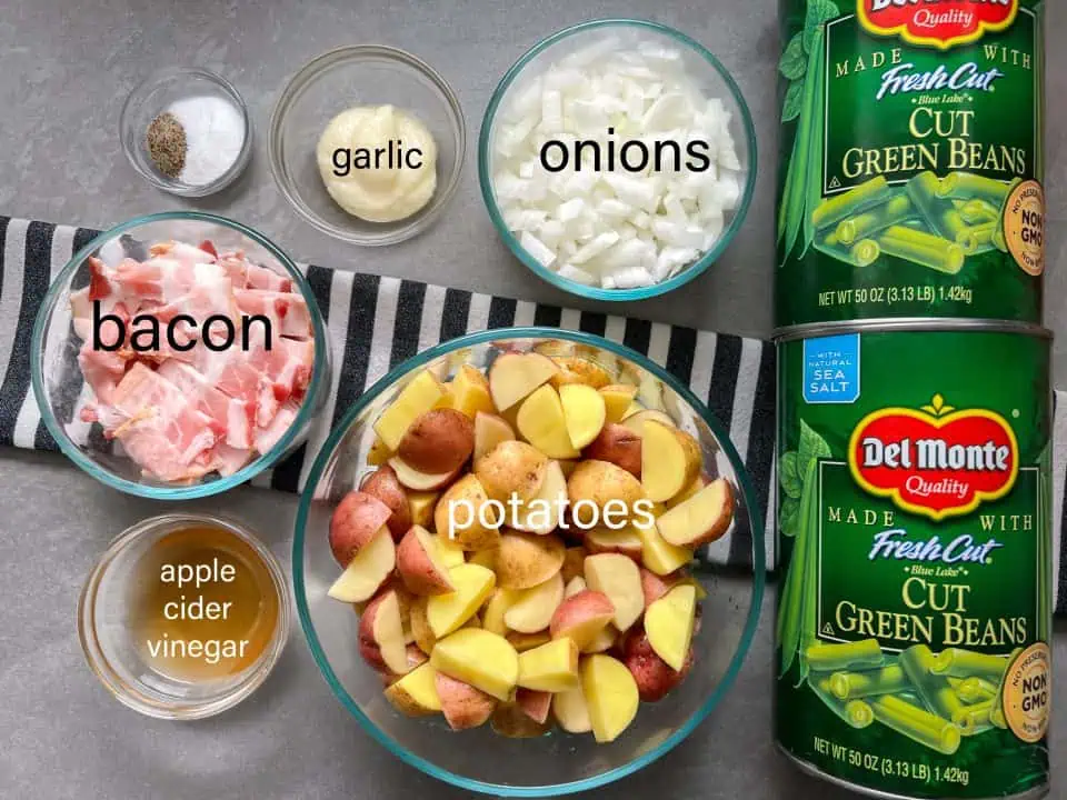 Ingredients for southern green beans including canned green beans, potatoes, bacon, onion, garlic, apple cider vinegar, salt, and pepper.
