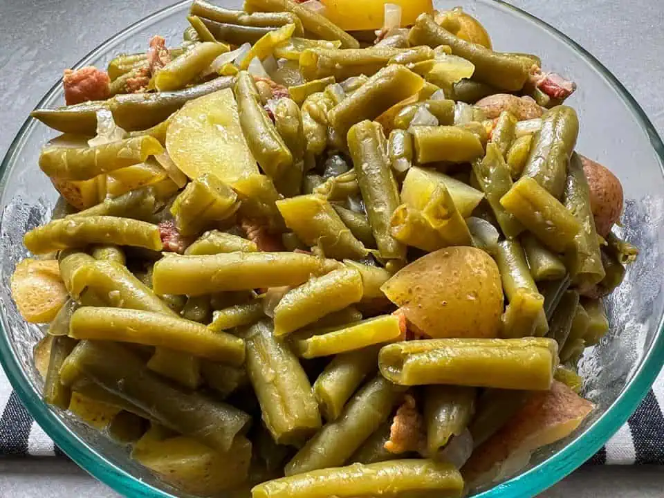 Bowl of southern green beans with potatoes, bacon, and onions.